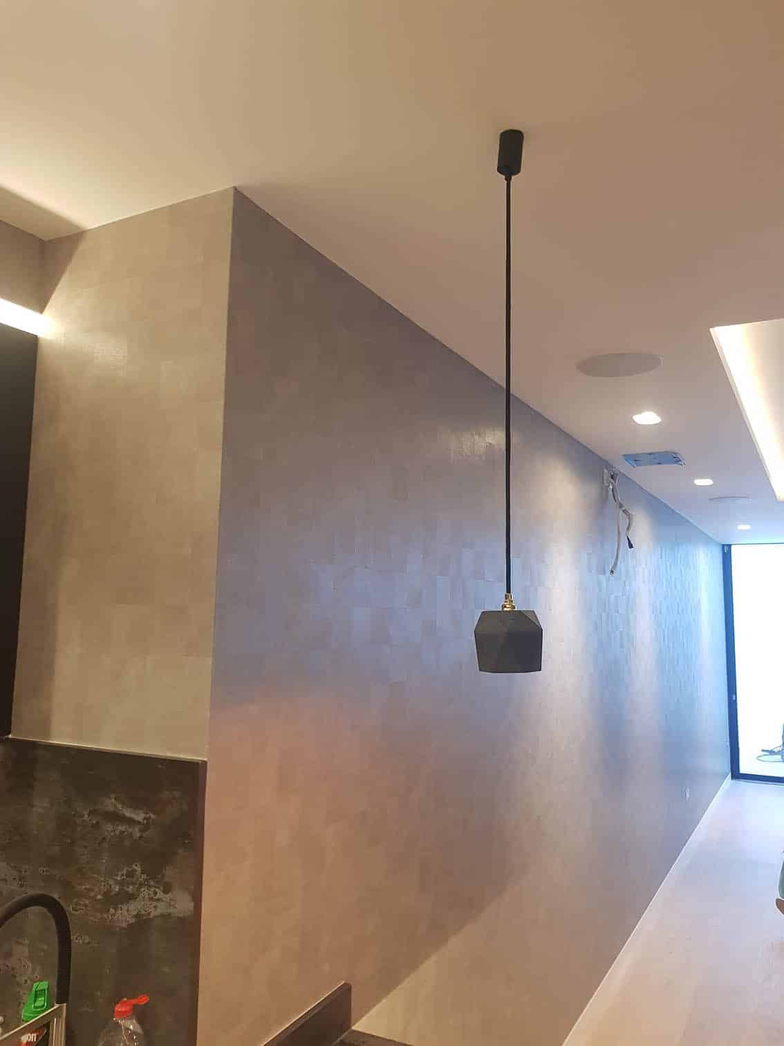 Armani Casa Designer wallpaper professionally installed by Bluespec Decorating Limited wallpaper hangers in London. Wallpaper is beige in colour and patterned. There are long hanging light from the ceiling.