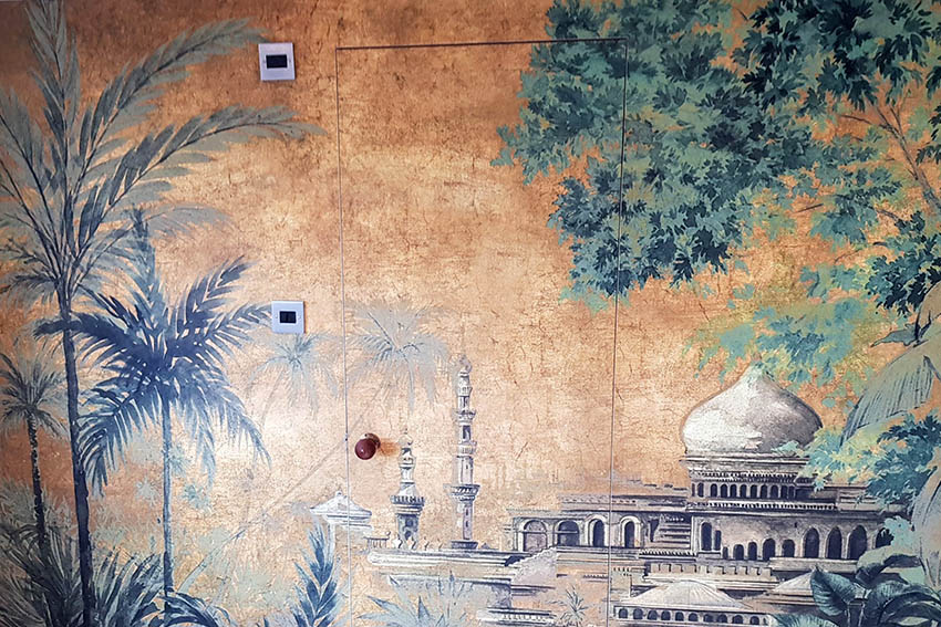 Made-to-measure Coordonne Random Chinoiseries Taj Mahal installed in a bedroom by Bluespec wallpaper hangers. The wallpaper has orange background, you can see Taj Mahal budling and some palm trees.