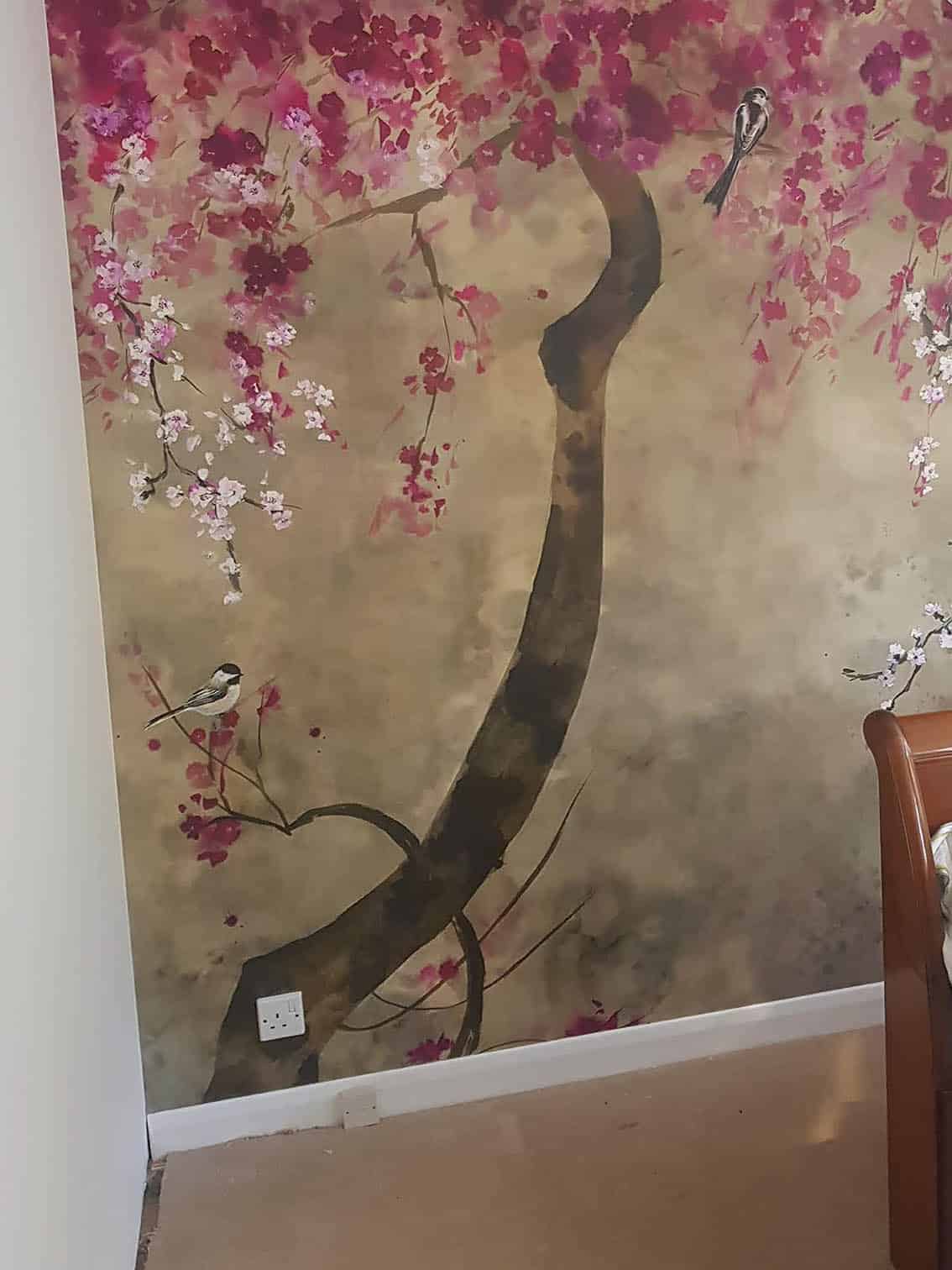 Designers Guild Shinsha wallpaper mural installation by our wallpaper hangers A beautiful tree with dark pink and white flowers on a light brown background. There are birds on the tree. The wall mural is a watercolour illustration