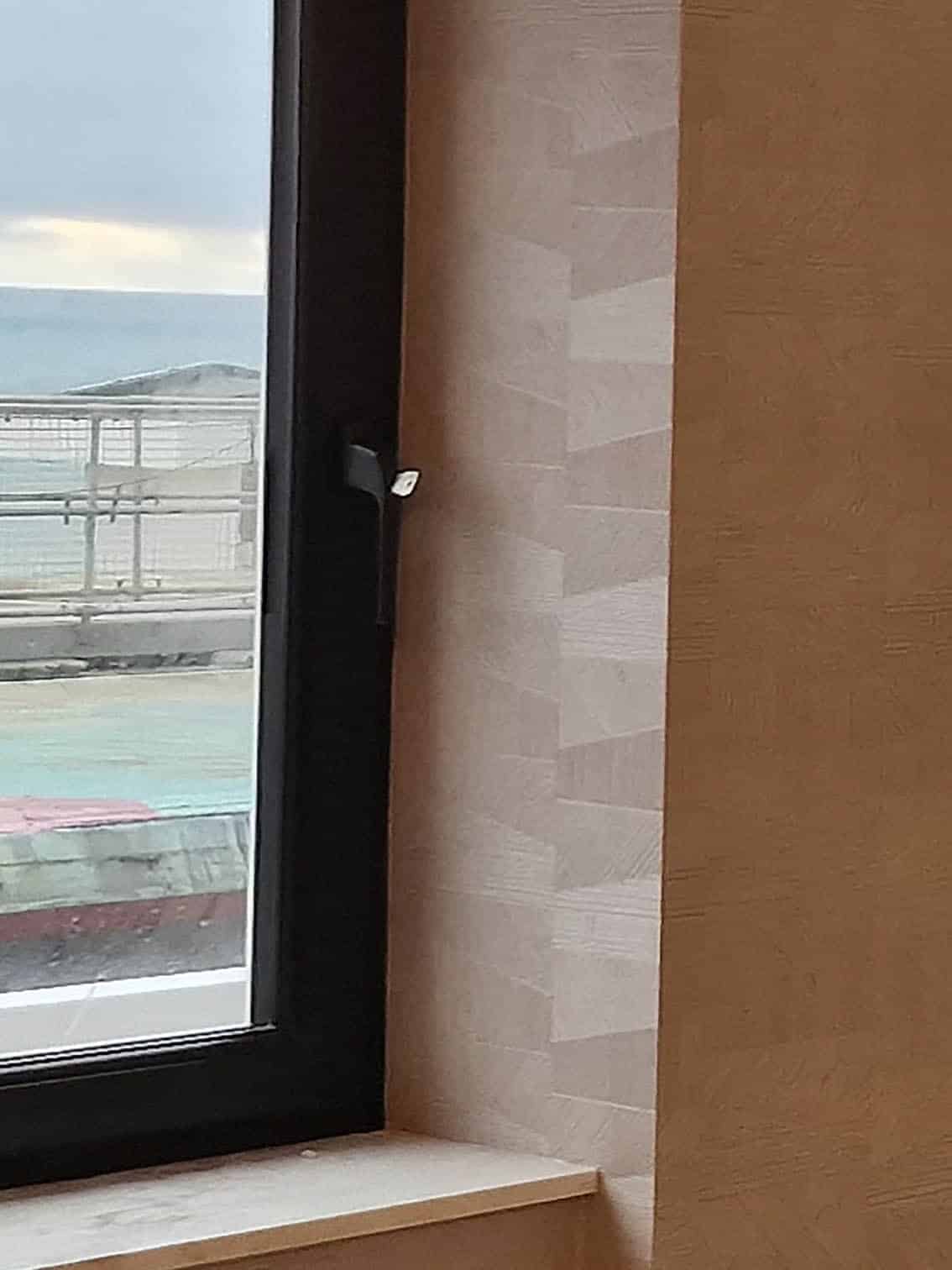 Arte wallpaper geometric in beige installed next to a window with an ocean view in Brighton