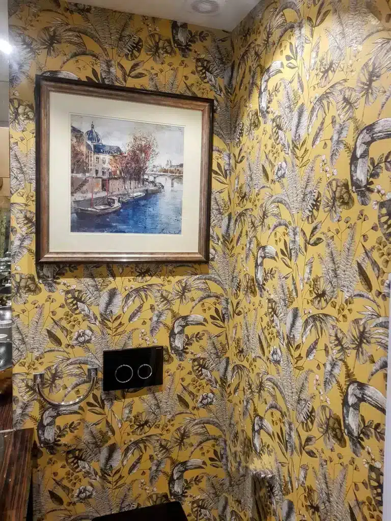 Patterned wallpaper in yellow colour professionally installed in a bathroom by Bluespec Decorating Limited.