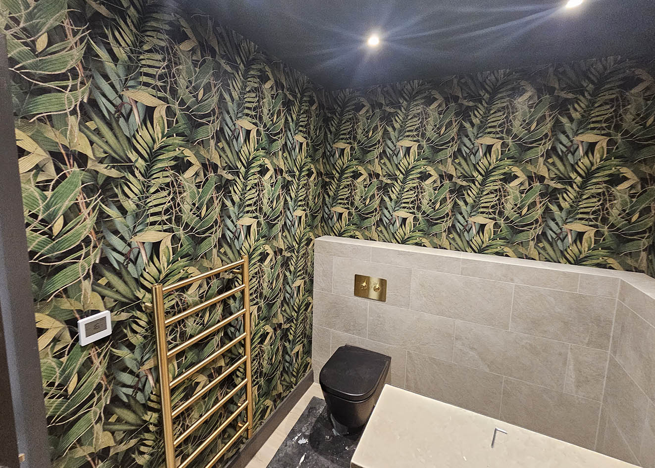 botanical-wallpaper-installation-bathroom-London Botanical wallpaper installed in a tiled bathroom in green and black, London by Bluespec wallpaper hangers.