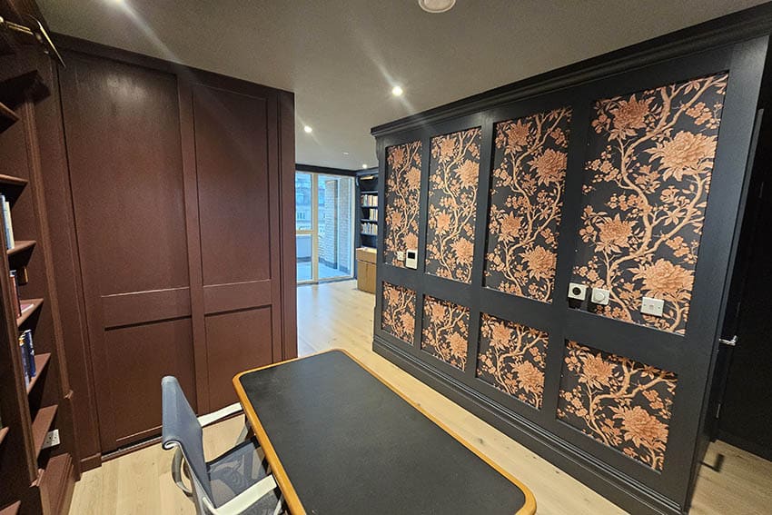 Patterned flowers wallpaper in dark brown and orange flowers installed on a feature wall in Camden Town, London by Bluespec Decorating Limited.