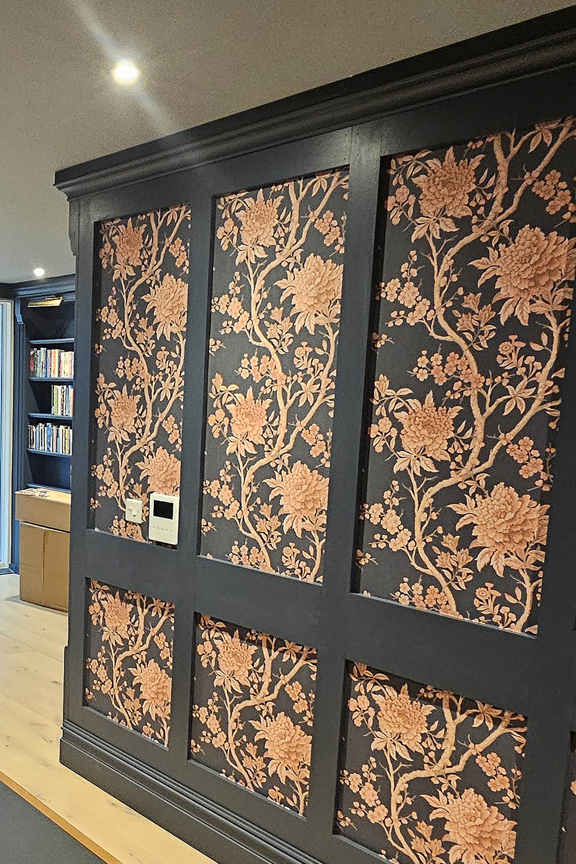 wallpaper-hanger-camden-town-london Wallpaper installed by a wallpaper hanger, Bluespec Decorating Limited in London. Dark grey frames and dark grey wallpaper background with dark orange large flowers.