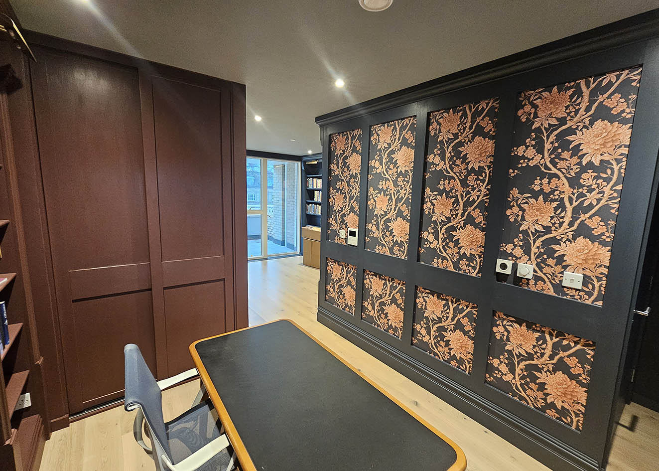 wallpaper-installer-camden-town-london Wallpaper installed on feature wall. The wallpaper has dark grey background and and huge dark orange flowers. It is in a flat in Camden Town, London.