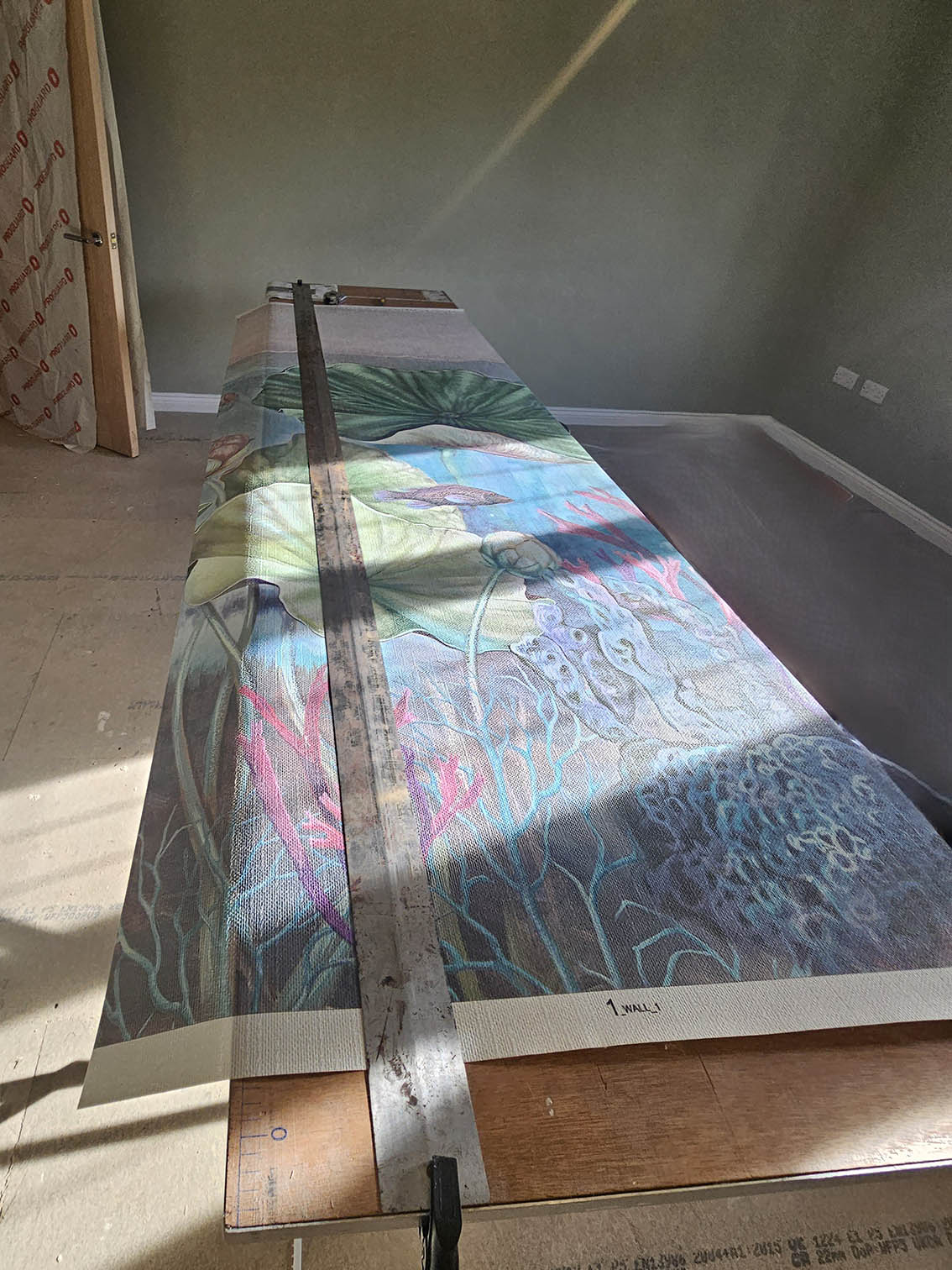 wallpaper-mural-installation-process Wallpaper mural on a wallpapering table. Work in a progress by Bluespec Decorating Limited.