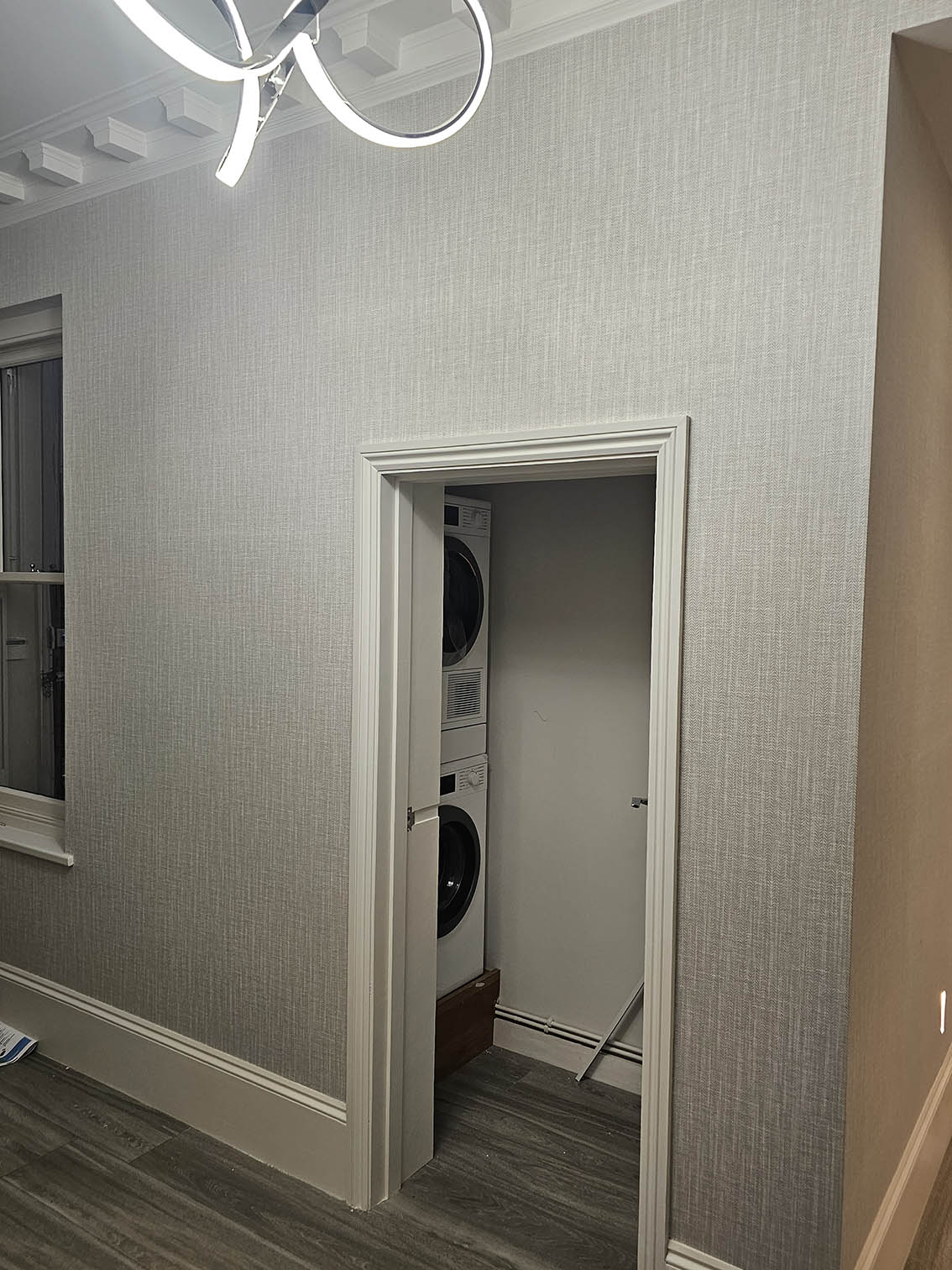 wallpaper-install-hallway-W11 Wallpaper installation in a hallway next to utility room with window and door. The wallpaper is grey.